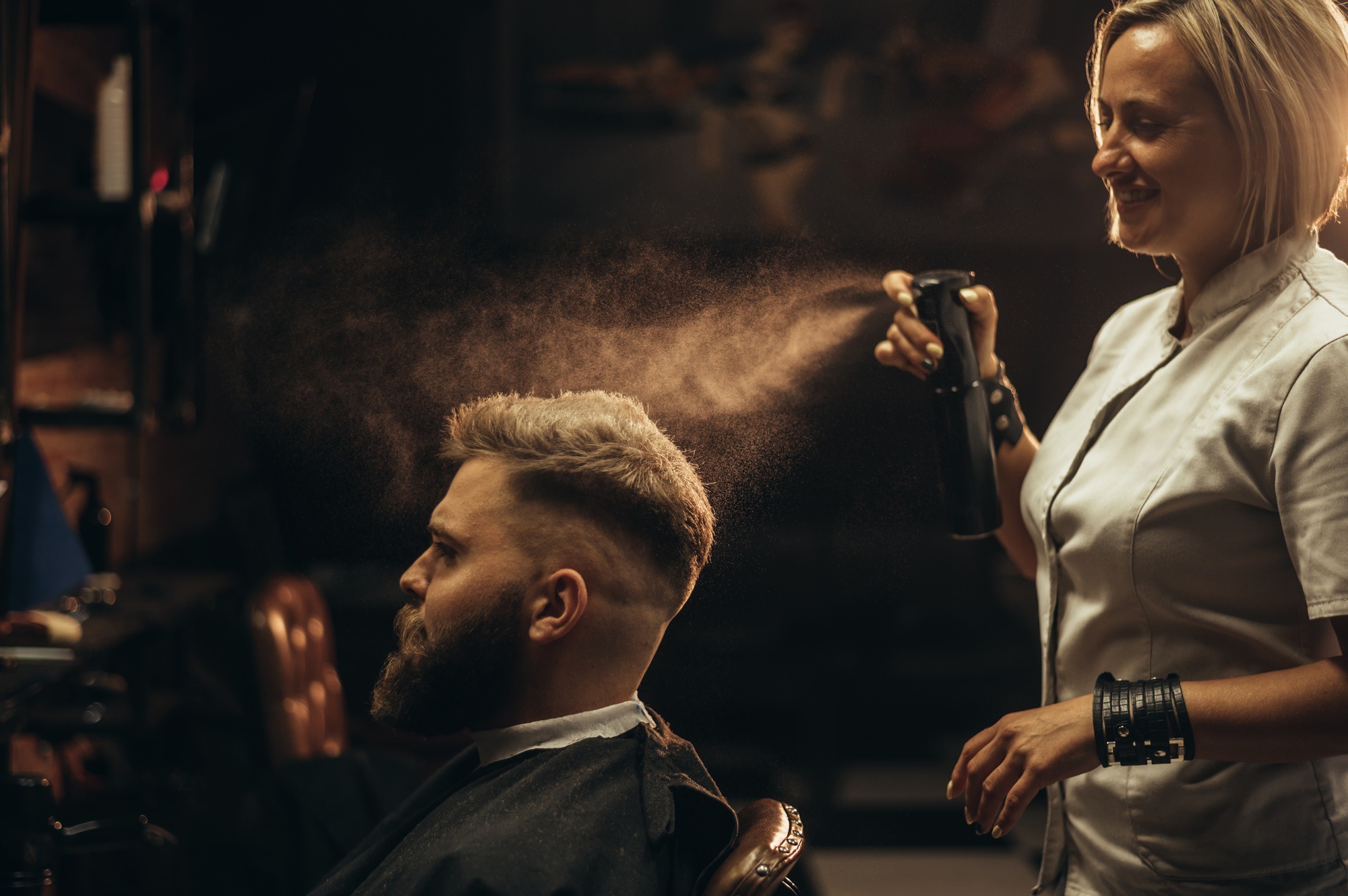 Young bearded man getting haircut by hairdresser